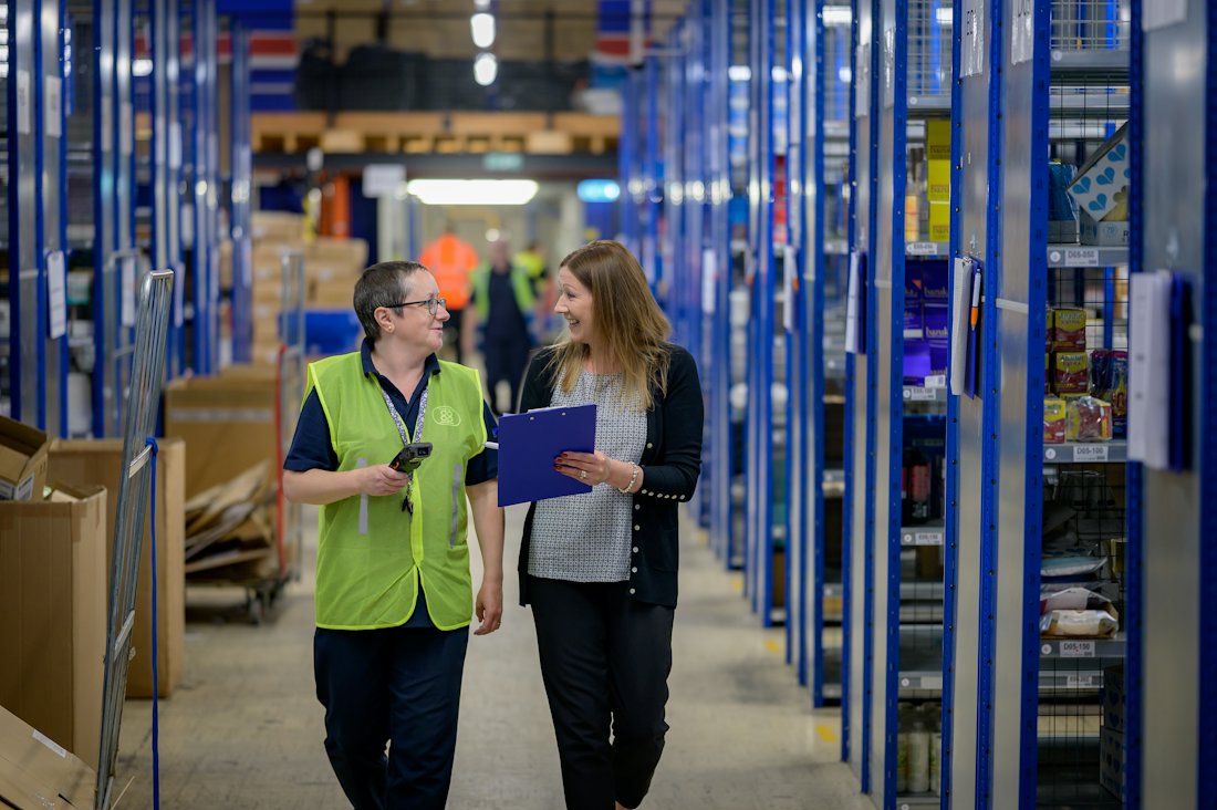 Two staff members walking through a clean, organised warehouse